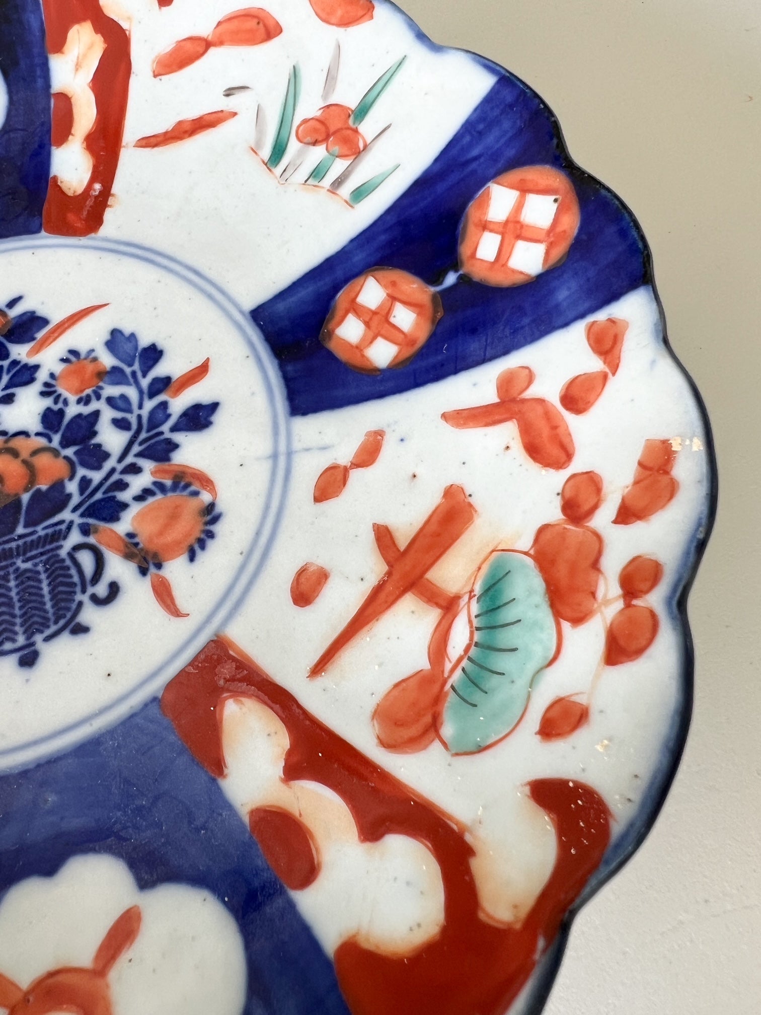 A close-up view of a hand-painted plate featuring scalloping along the edges