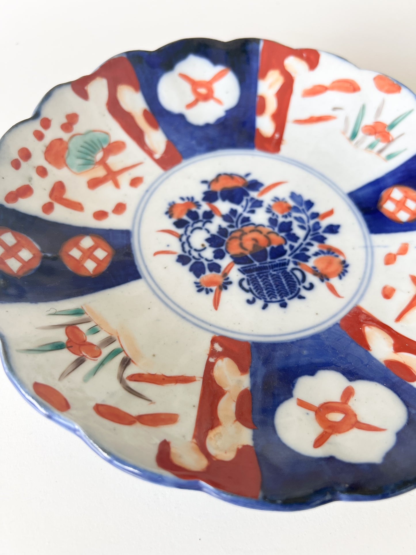Close-up of a plate featuring a red, white, and blue design. he plate's rim is scalloped and painted a dark blue