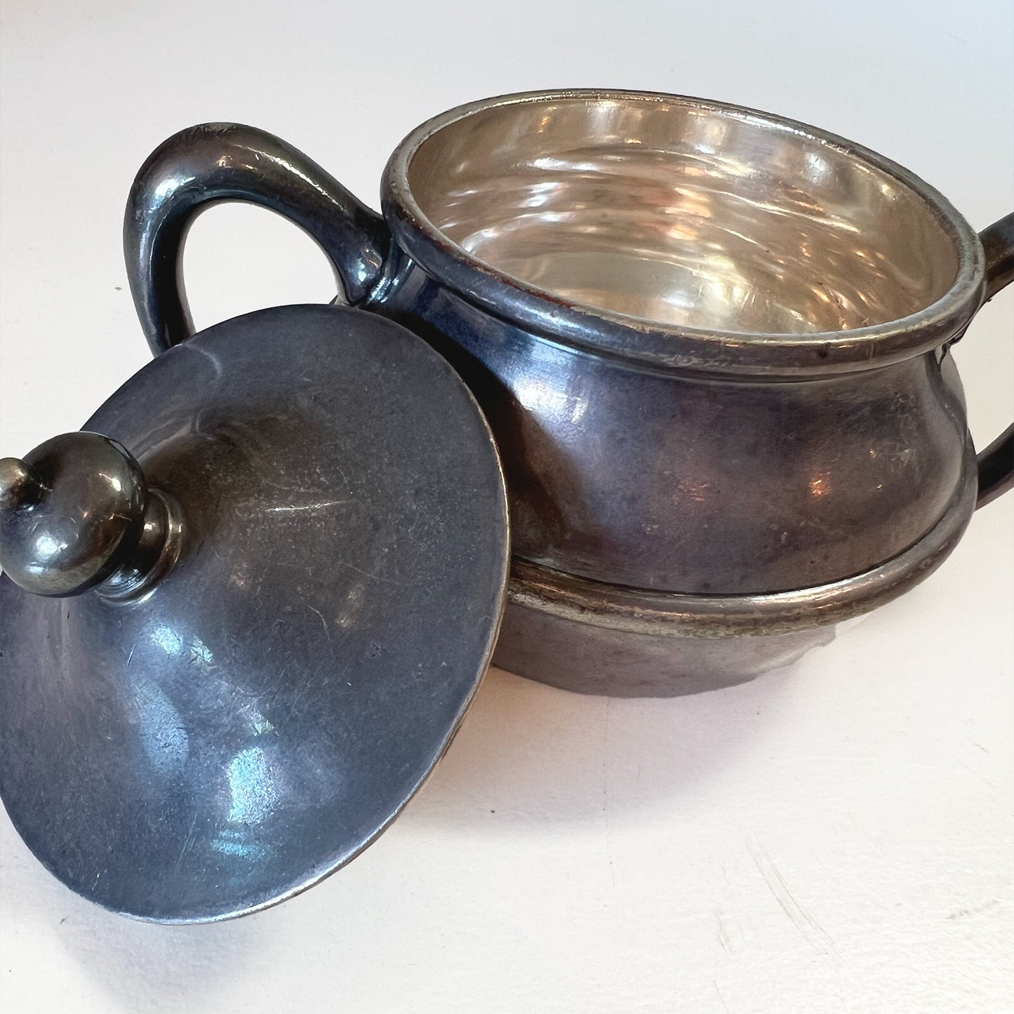 Silver soldered sugar bowl with lid, displayed in a 3/4 view with the lid off, revealing the shiny, bright silver inner surface of the bowl